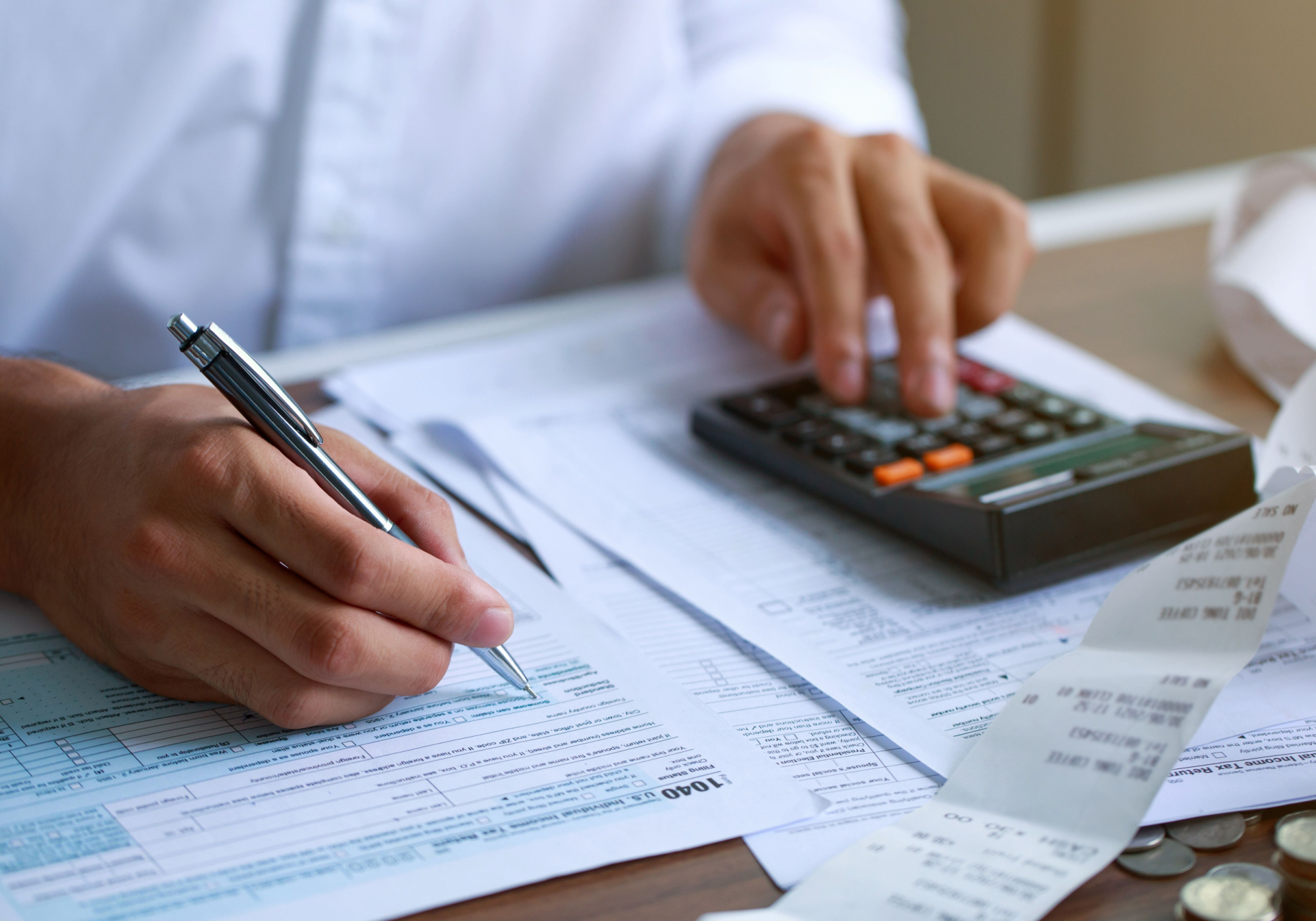 Man completing 1040 tax form while using calculator 