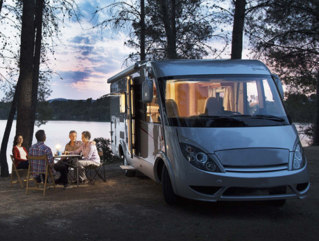 family sitting next to lake and RV