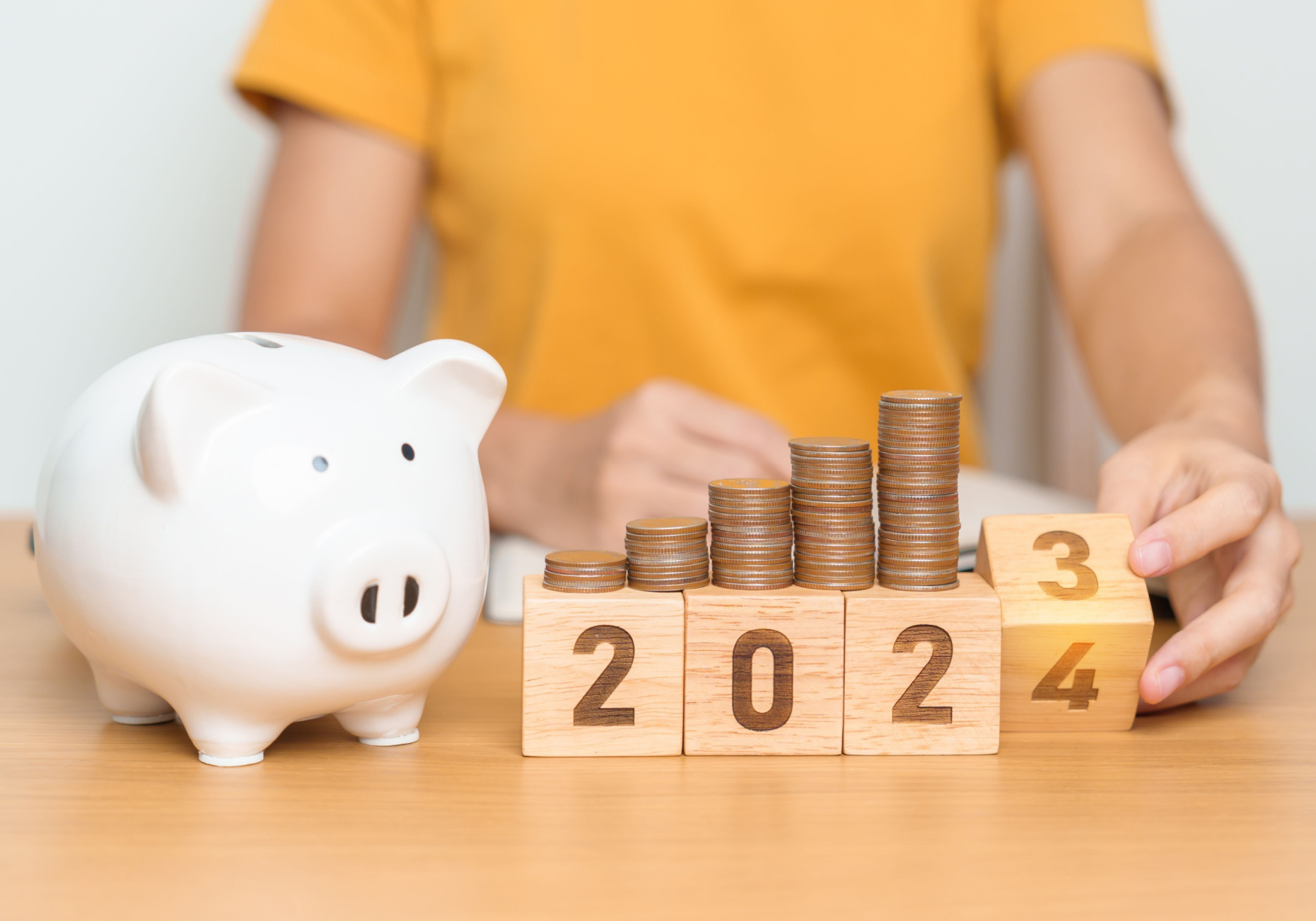 2024 blocks with coins stacked on top, next to white piggy bank
